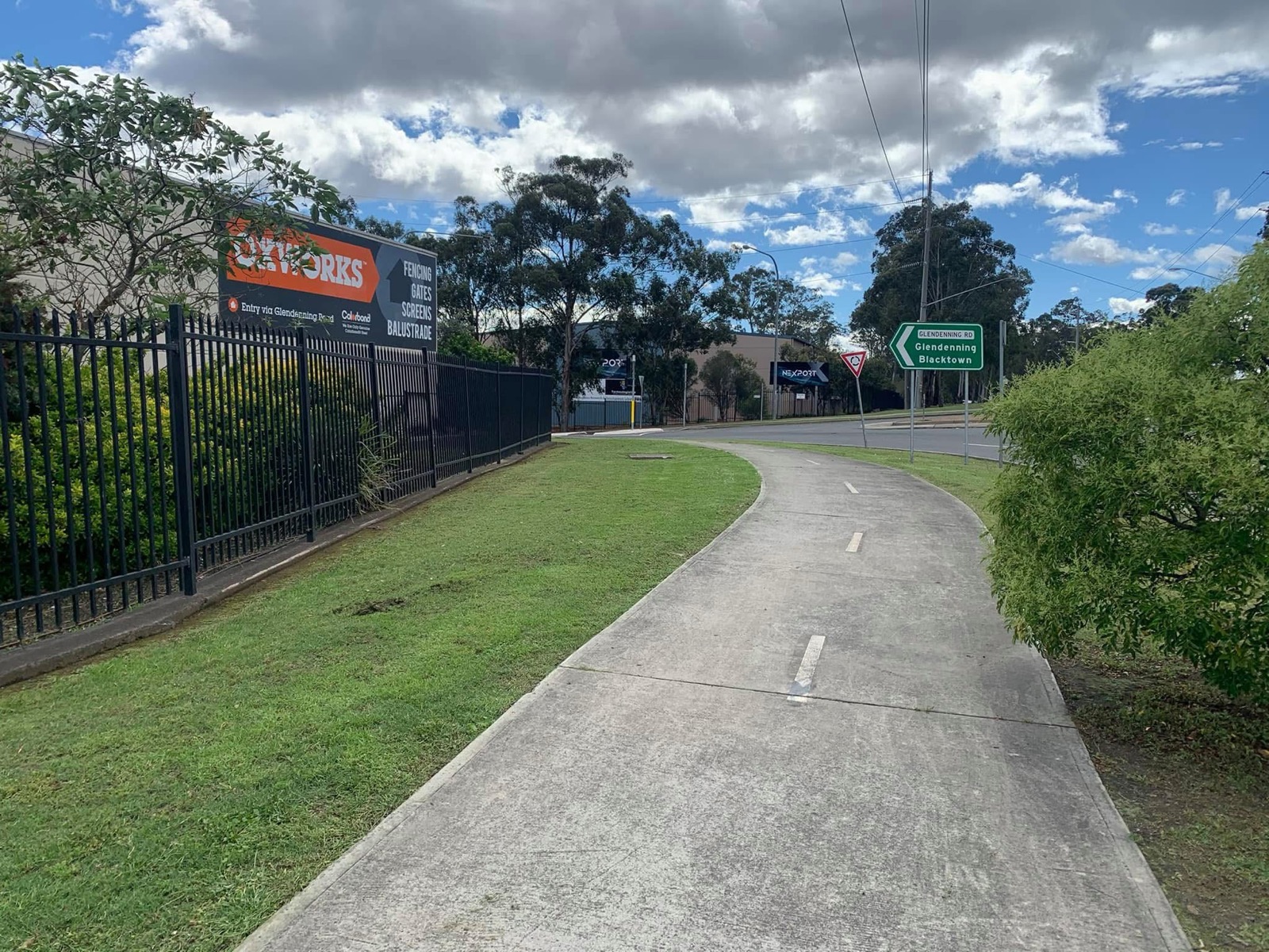 Cut grass and shaped shrubs along an industrial street frontage